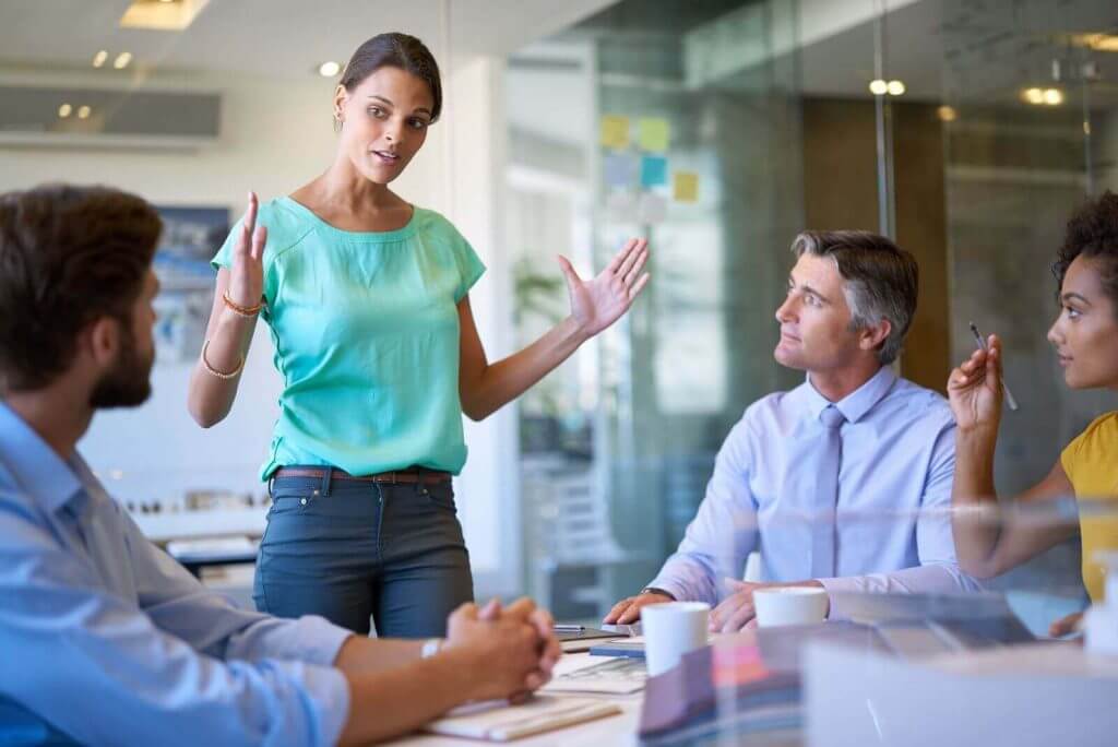 A woman is giving a presentation to a group of people in a conference room