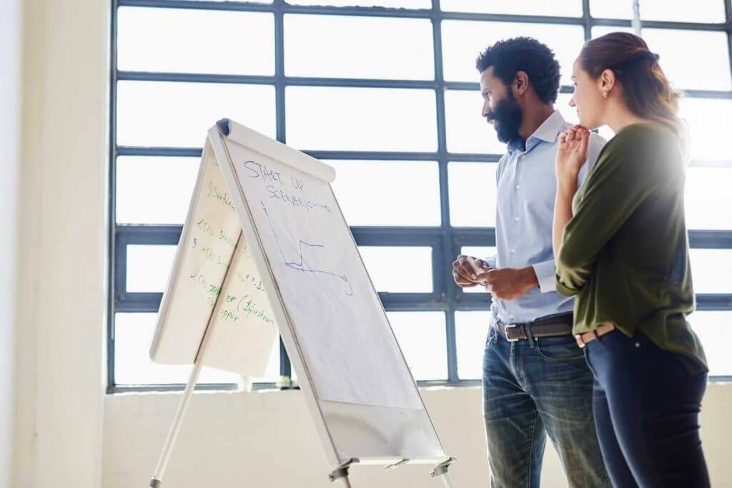 Two people standing in front of a whiteboard