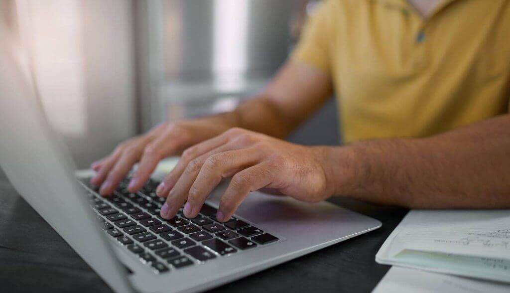 Person working on a laptop with focus on their hands on the keyboard