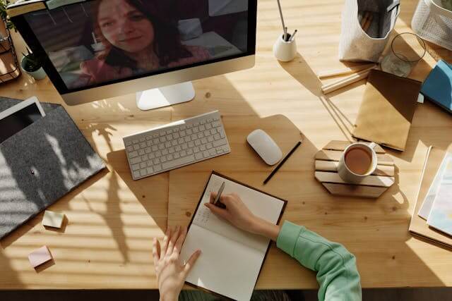 Person taking notes during a video call in a well organized workspace