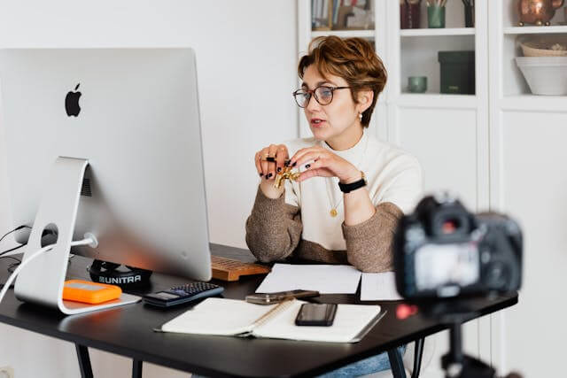 A person recording a video or conducting a webinar while working at a computer desk