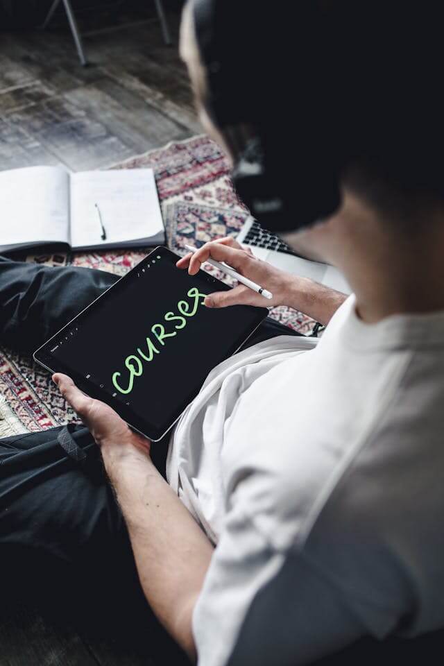 Person sitting on the floor taking notes on a tablet with a stylus