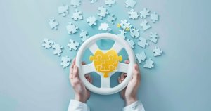 hands holding a steering wheel shaped puzzle with interlocking pieces on a light blue background.