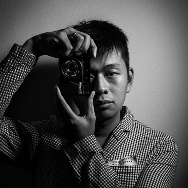 A man holding a camera in front of a wall.